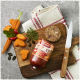 FLEISCHESLUST 'Zartes Rind' Futterrolle auf einem Holz‑Schneidebrett mit geschnittenen Karotten, Kürbiskernen und einem Messer.