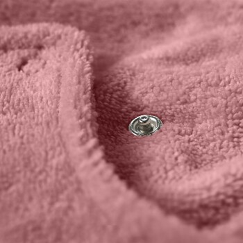 Nahaufnahme einer weichen rosa Haustierdecke mit einem silbernen Druckknopf, die ihre gemütliche Textur und sichere Befestigung hervorhebt.