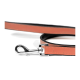 Nahaufnahme einer stilvollen Hundeleine mit einem schlanken, orangefarbenen Lederband mit schwarzer Einfassung und einem glänzenden Metallclip zur Befestigung.