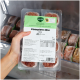 Hand hält verpackte BARFER'S Complete 'Komplett‑Mix Rind' Rohfutter-Schale (400 g) im Gefrierschrank.