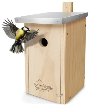 Ein Holzvogelhaus mit einem Metalldach, graviert mit "Wildlife Home", während ein Kohlmeise sich dem Eingang nähert.