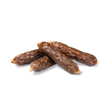 Four chewy, brown dog treats resembling sausages, stacked on a white background.