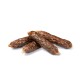 Four chewy, brown dog treats resembling sausages, stacked on a white background.