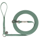 Eine grüne Gummihundeleine, ordentlich aufgerollt, mit einem Metallclip und einem silbernen Anhänger mit dem eingravierten Markennamen 'Trixie'.