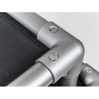 Nahaufnahme einer silbernen Metallrahmen-Ecke mit Schrauben, die an einem schwarzen Netzstoff befestigt ist, wahrscheinlich Teil eines Haustierbettes oder einer Tragetasche.