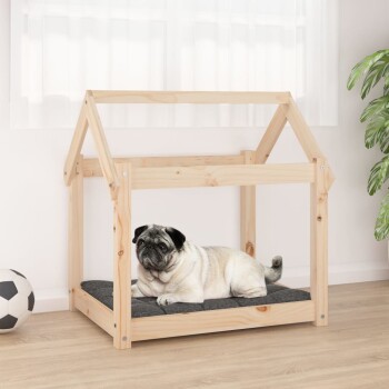 Ein Mops, der auf einem dunkelgrauen Kissen in einem hölzernen Haustierhaus mit Dach ruht, das auf einem hellen Holzboden steht. Ein Fußball liegt in der Nähe.