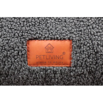 Grauem Sherpa-Stoff eines Haustierbetts mit orangefarbenem Lederetikett mit der Aufschrift 'PETLIVING place to enjoy' und Pfoten-im-Haus-Logo.