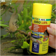 Une main tient un récipient jaune de nourriture pour axolotls JBL Pro Novo Lotl, avec des images d'axolotls et un texte mettant en avant 40% de contenu en truite.