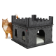 Eine verspielte orangefarbene Katze steht neben einem grauen Filz-Katzenhaus in Form einer Burg mit gewölbten Eingängen und einem weichen Innenraum.
