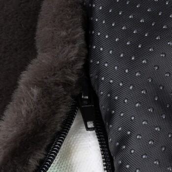 Nahaufnahme eines Haustierbettes mit einem weichen, dunklen Fellfutter und einem strukturierten schwarzen Äußeren mit einem Reißverschluss.