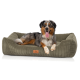 Ein glücklicher Australian Shepherd, der auf einem plüschigen, olivgrünen Hundebett mit einem strukturierten Cord-Design und einem Lederetikett entspannt.