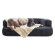 Zwei Hunde ruhen sich auf einem plüschigen schwarzen Hundesofa aus, das mit einer weichen beigen Decke bedeckt ist. Ein Hund ist eine große braune Rasse, der andere ein kleiner schwarzer Pudel.