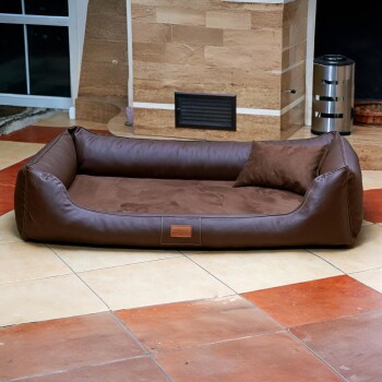 Braunes Leder- und Wildleder-Haustierbett mit passendem Kissen auf gefliestem Boden in gemütlicher Innenraumumgebung.