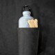 Eine hellblaue Wasserflasche und Hundeknochen-Leckerlis sind teilweise in einer schwarzen Stofftasche sichtbar.