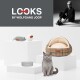 Eine graue Katze sitzt neben einem gemütlichen karierten Haustierbett, zwei Spielmäusen und einer grauen Futterschüssel mit der Aufschrift "LOOKS" von Wolfgang Joop, auf weißen Podesten.