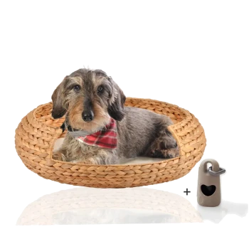 Ein gemütliches gewebtes Hundebett mit einem grauen Hund, der ein rotes Karobandana trägt und darin ruht, begleitet von einem kleinen herzförmigen Etikett.