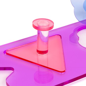 Buntes Kunststoff-Haustierspielzeug mit einem pinken runden Stift auf einer lila Basis mit einem dreieckigen Ausschnitt, entworfen für interaktives Spielen.