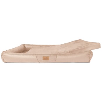 Beiges Hundebett mit einer plüschigen Oberfläche und erhöhten Rändern, mit einem kleinen Lederetikett mit dem Markennamen.