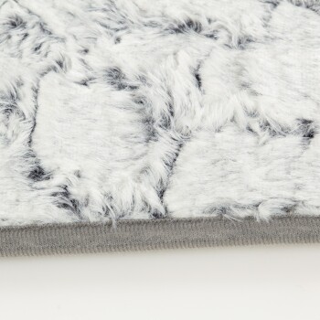 Nahaufnahme einer weichen, flauschigen Haustierdecke mit einem weißen und grauen Fellmuster, mit einem grauen Rand entlang der Kante.