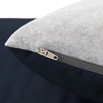 Nahaufnahme eines Haustierbettes mit einer weichen grauen Fleece-Oberseite und einem dunklen marineblauen Boden, mit einem sichtbaren Reißverschluss für einfache Entfernung und Reinigung.
