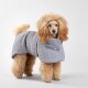 Ein flauschiger, hellbrauner Hund trägt einen gemütlichen grauen Kapuzenpullover mit Waffelmuster und steht vor einem schlichten weißen Hintergrund.