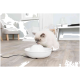 Eine flauschige weiße Katze mit grauen Markierungen trinkt aus einem modernen weißen Haustier-Wasserbrunnen auf einem Holzboden in einem hellen Raum.