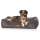 Ein Hund, der auf einem plüschigen, grauen Cord-Haustierbett mit einem Lederschild liegt, auf dem "Pet Comfort" steht.