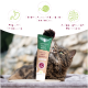 Eine Katze, die nach einer Tube "Katzen Malz Paste" greift, die mit "Natürliche Anti-Haarball" beschriftet ist, mit Symbolen, die die Verdauungsregulation und Haarballenunterstützung anzeigen.