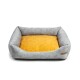 Graues Haustierbett mit einem weichen gelben Kissen in der Mitte, mit erhöhten Seiten für Komfort und einem kleinen Lederschild an der Seite.