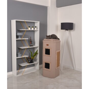 Ein gemütlicher Katzenbaum mit einer weichen Oberseite und zwei Öffnungen steht neben einem modernen weißen Regal mit dekorativen Pflanzen und einer Lampe. Eine graue Katze liegt oben.