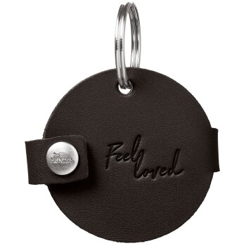 Runder schwarzer Lederanhänger für Haustier mit geprägtem „Feel loved“-Schriftzug, silbernem Druckknopf und Metall-Splittring.