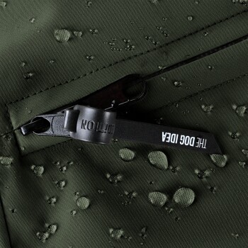 Nahaufnahme eines grünen wasserdichten Stoffes mit Wassertropfen, ausgestattet mit einem Reißverschluss-Zipper mit dem Text 'DIE HUND IDEE.'