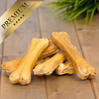 Ein Stapel hochwertiger Hundekauartikel auf einer Holzoberfläche, mit einem goldenen "PREMIUM"-Label in der oberen linken Ecke.