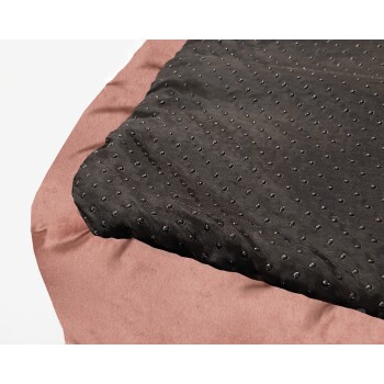 Eine Nahaufnahme eines Hundebettes mit einer schwarzen strukturierten Oberfläche mit erhöhten Punkten und einem weichen rosa Rand.