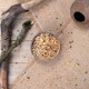 Eine Holzschüssel, gefüllt mit einer bunten Mischung aus Vogelfutter, steht auf einer Juteschicht, umgeben von verstreutem Futter und natürlichen Zweigen.