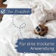 Braun-weißer Hund liegt auf dem Rücken auf einem weißen Bett; blaue Hinweise: 'Ohne Rückstände' und 'Für eine trockene Anwendung.'