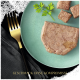 Ein grüner Teller mit Haustierfutter-Pâté, kleinen Würfeln und Petersilie; eine goldene Gabel daneben. Text: "GESCHMACK OHNE KOMPROMISSE."