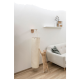 Eine verspielte orange Katze streckt sich nach einem hängenden Kratzbaum in einem modernen Wohnzimmer mit einem hellen Sofa und einem dekorativen Regal.