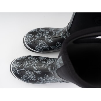 Schwarze Gummistiefel mit floralem Muster, mit weißen Umrissen von Blättern und Blumen, von oben betrachtet.