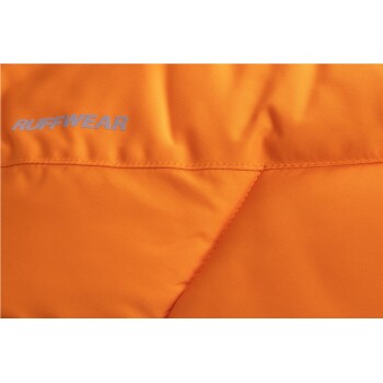 Nahaufnahme einer orangefarbenen Hundejacke mit dem Markennamen "RUFFWEAR" in silberner Schrift.