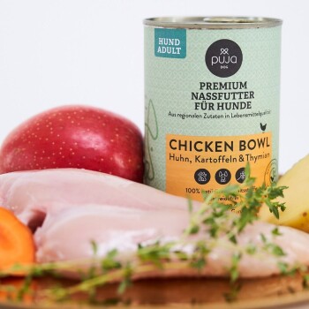 Eine Dose Premium-Hundefutter mit der Aufschrift "Chicken Bowl" mit Zutaten wie Huhn, Kartoffeln und Thymian, umgeben von frischen Produkten.