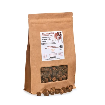 Braune Papiertüte mit Hundeleckerlis, beschriftet mit "KYLLINGETERN" mit einem Fenster, das kleine, quadratische Leckerlis zeigt; mit einem Hundebild und Nährstoffinformationen.