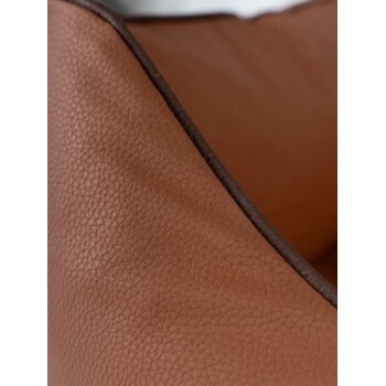 Nahaufnahme eines braunen, strukturierten Leder-Haustierbetts mit dunkelbrauner Paspelierung aus einem Online-Tiergeschäft.