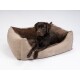 Ein Schokoladen-Labrador ruht sich in einem plüschigen beigen Hundebett mit braunem Innenraum aus, mit "TrendPet" auf der Seite gestickt.