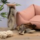 Ein Glasbehälter mit großen, getrockneten Tierohren steht neben einem rosa Haustiersofa auf einem Holztisch, mit zwei geknoteten Seilspielzeugen in der Nähe.