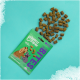 Grüne Verpackung von Edgard Cooper Hundebissen mit Cartoon-Hunden auf der Vorderseite, verstreute Leckereien auf einem türkisfarbenen Hintergrund.