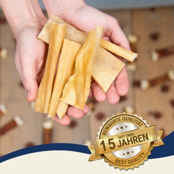 Hände halten verschiedene Hundekauartikel in verschiedenen Formen, mit einem goldenen Abzeichen, das "Beste Qualität" und "10 Jahre" sagt.