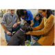 Ein brauner Hund mit einem blauen Halsband wird sanft von einer Frau in einem gelben Shirt und einem Kind in einem blauen Shirt in einem Tiergeschäft gestreichelt.