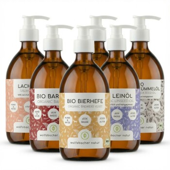 Sechs Flaschen organischer Tieröle: Lachs, Leinsamen, Schwarzkümmel und Bierhefe, jeweils mit Nährstoffvorteilen für alle Haustiere beschriftet.