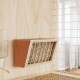 Eine Holzfütterungsstation für Haustiere, die an einer hellen Holzwand montiert ist, mit einem lamellenförmigen Design und mit Stroh gefüllt, neben einem Wasserspender.